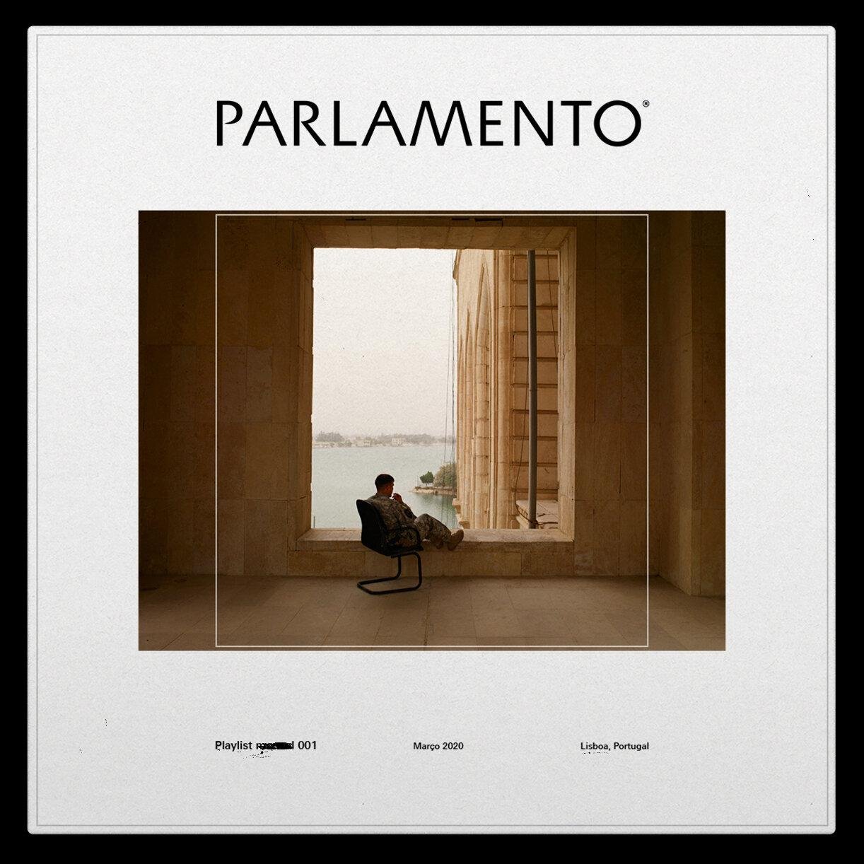 A person sits on a chair in a large stone window frame, gazing at a serene waterfront view.