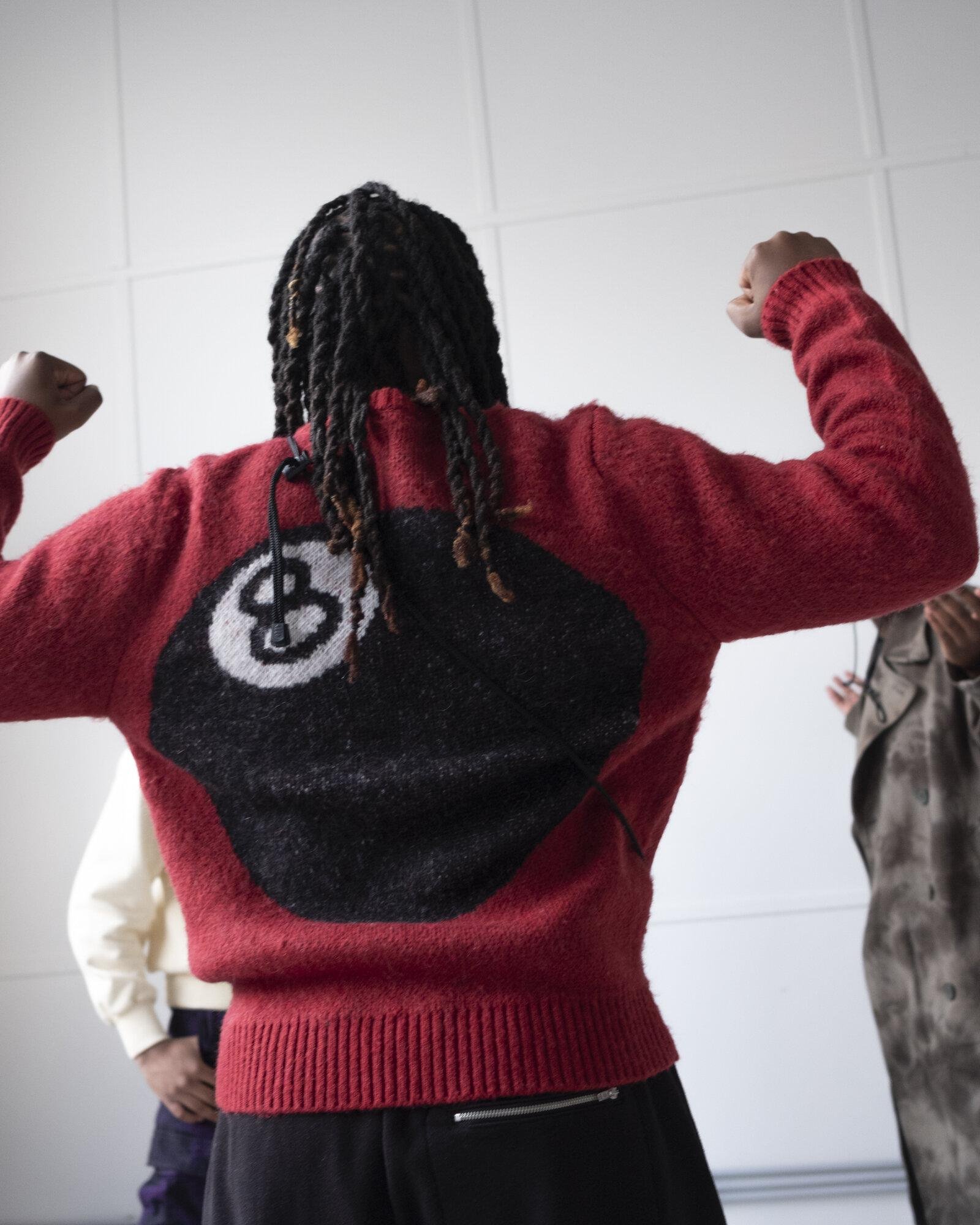 Person with a 8-ball knitted on the back for Visual Installment 4.