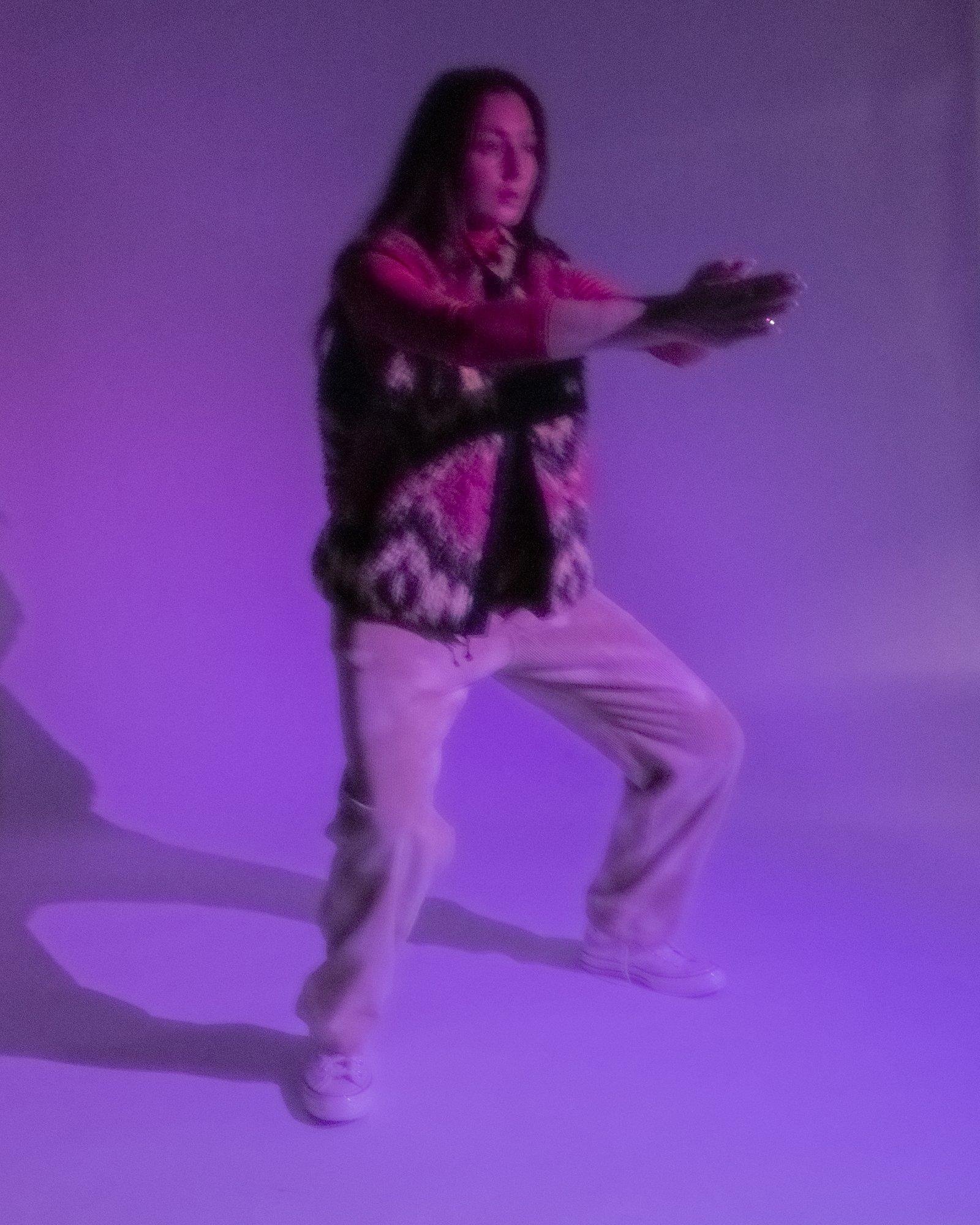 Model posing for Visual Instalment 9 in violet lighting.
