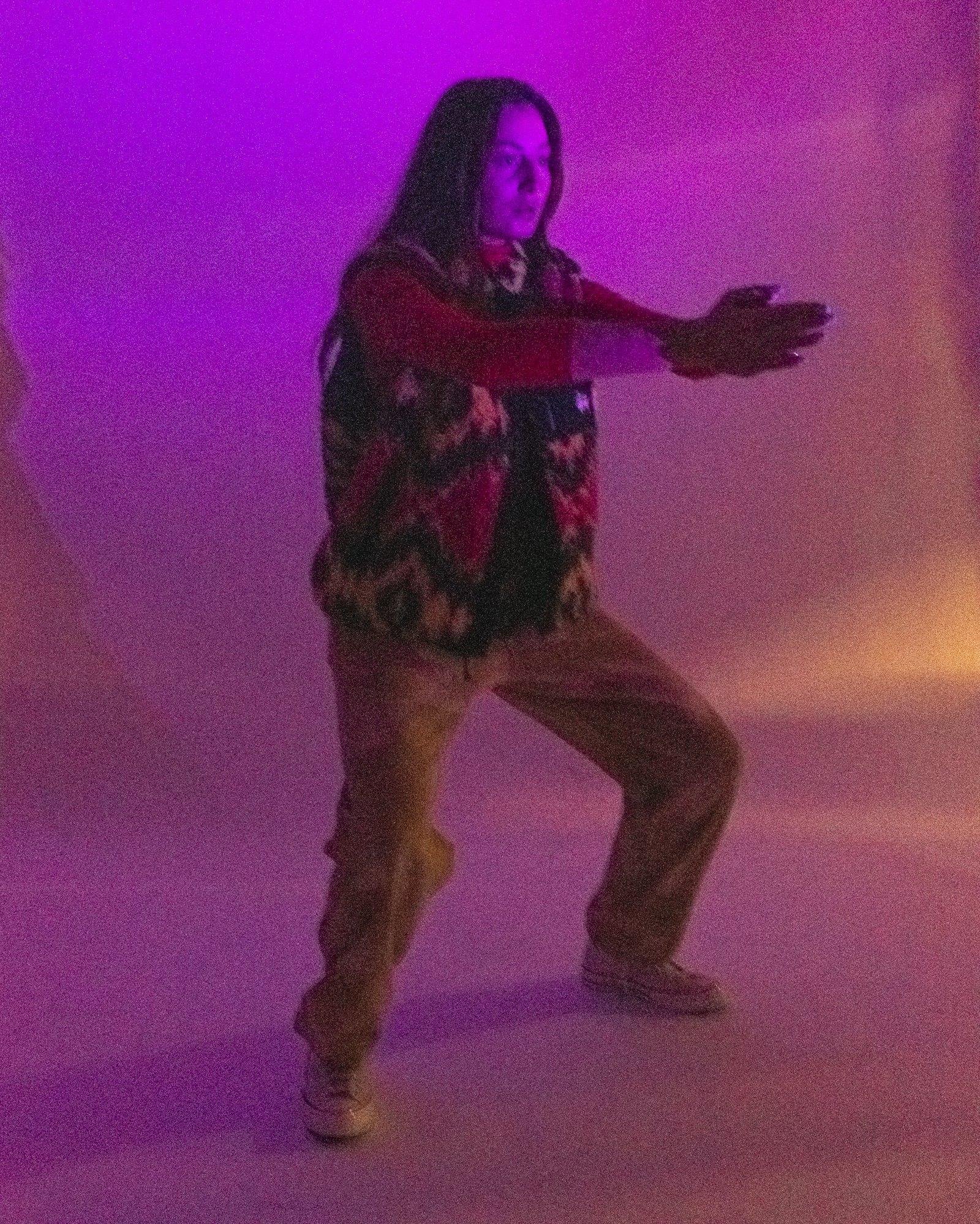 Model posing for Visual Instalment 9 in purple and pink lighting.