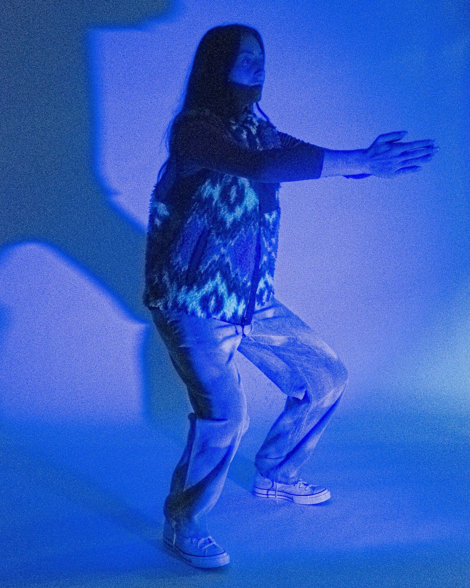 Model posing for Visual Instalment 9 in dark blue lighting.
