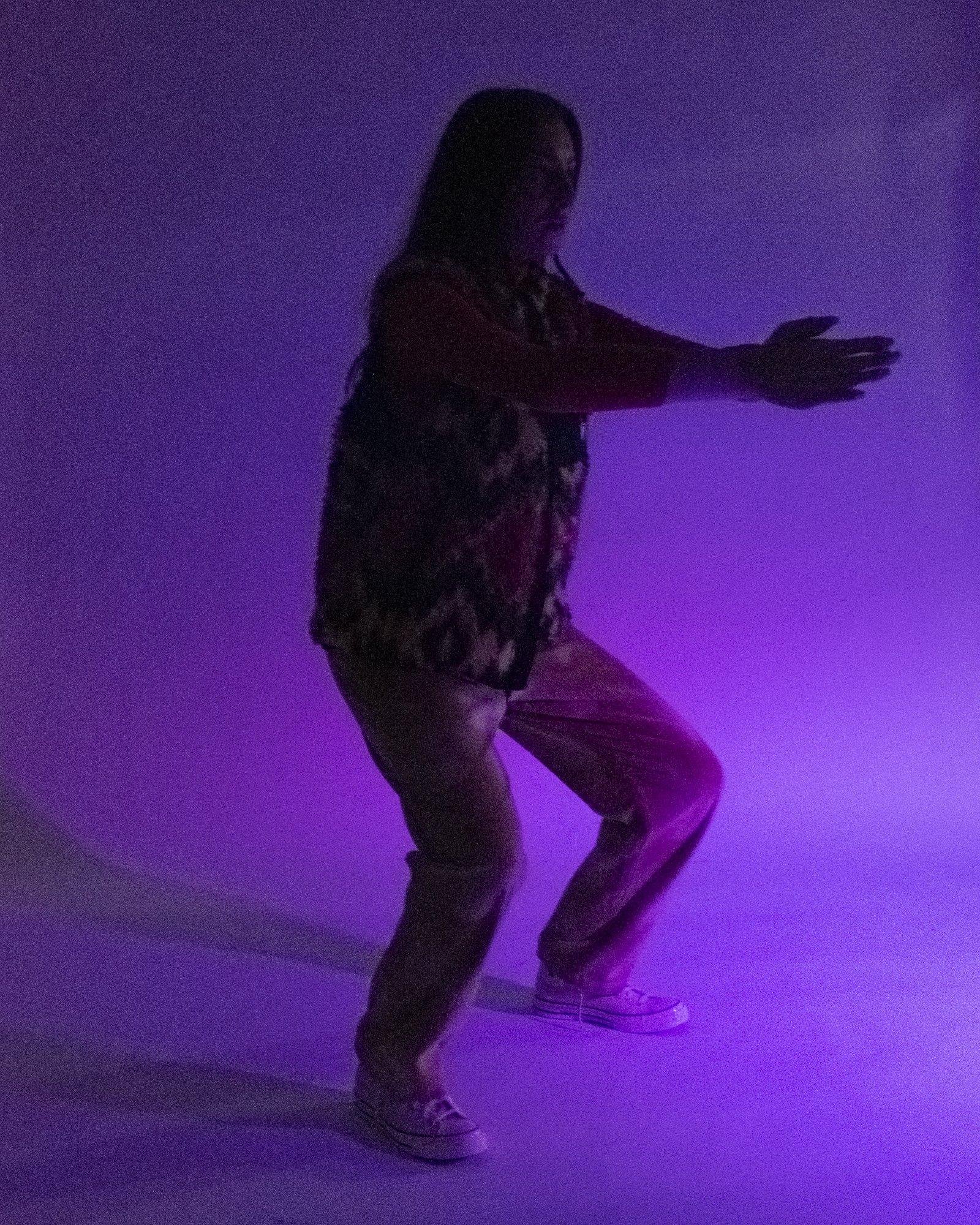 Model posing for Visual Instalment 9 in purple lighting.