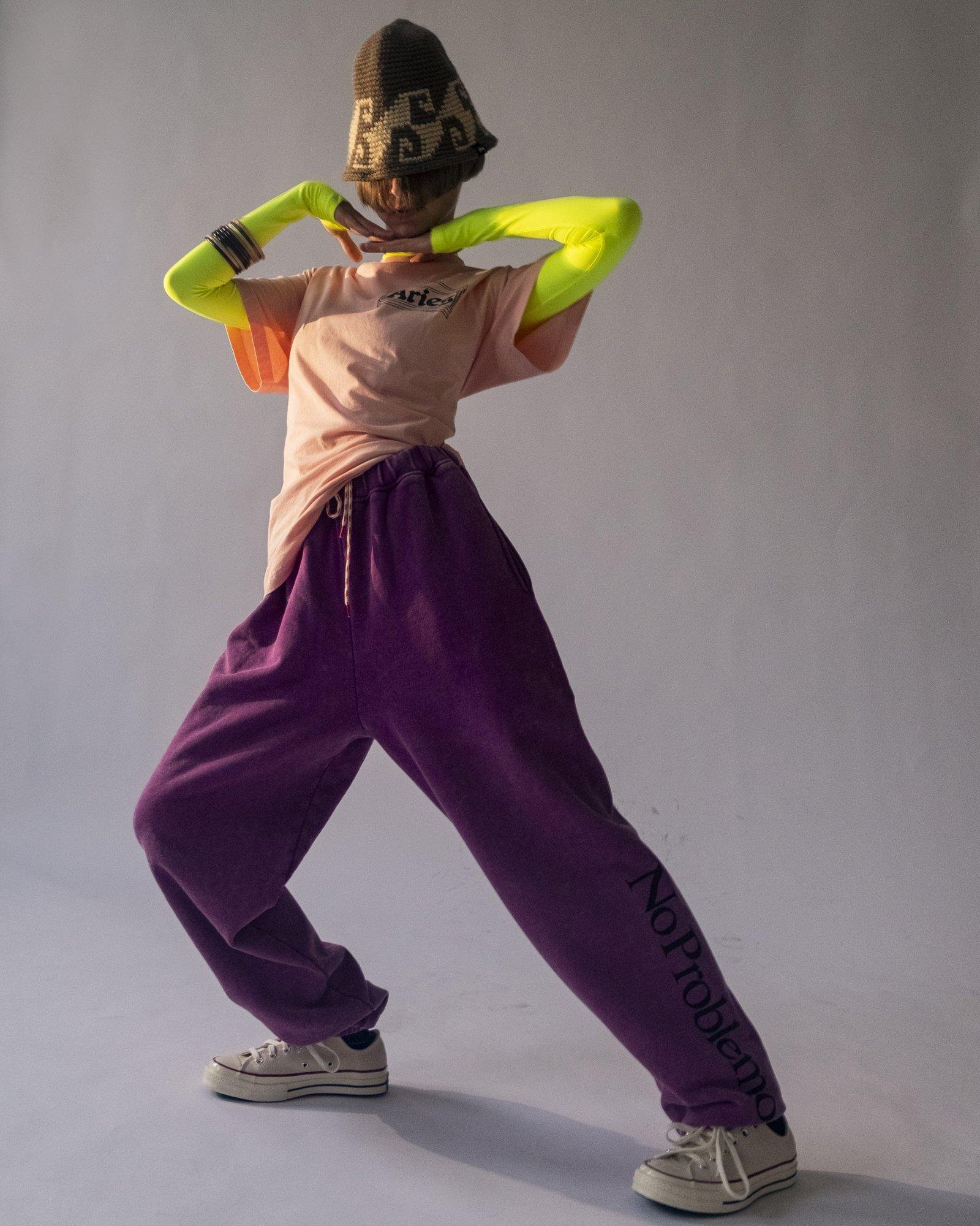 Model posing for Visual Instalment 9 over a grey background.