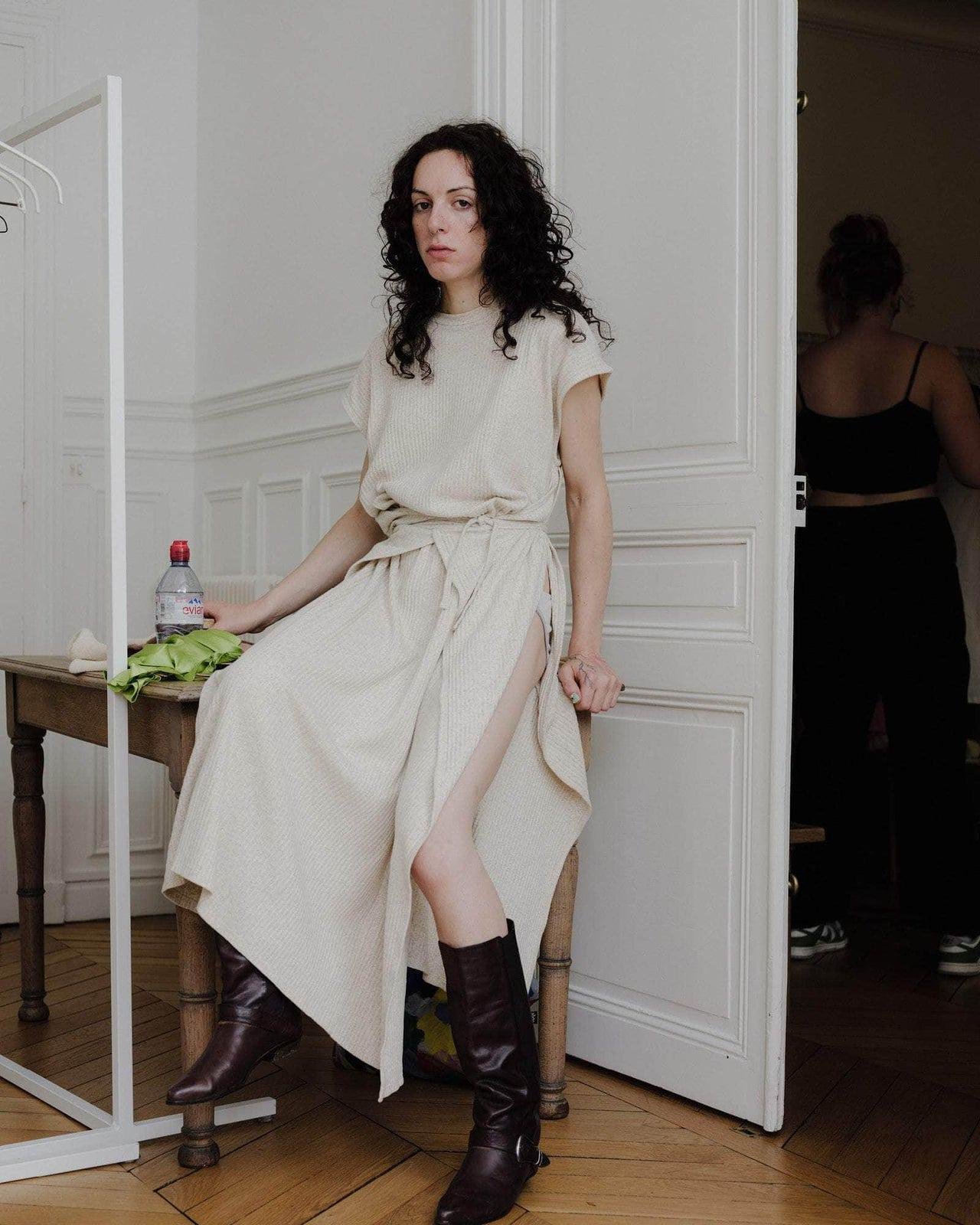 Model sitting wearing the Baserange Shaw Sleeveless Dress.