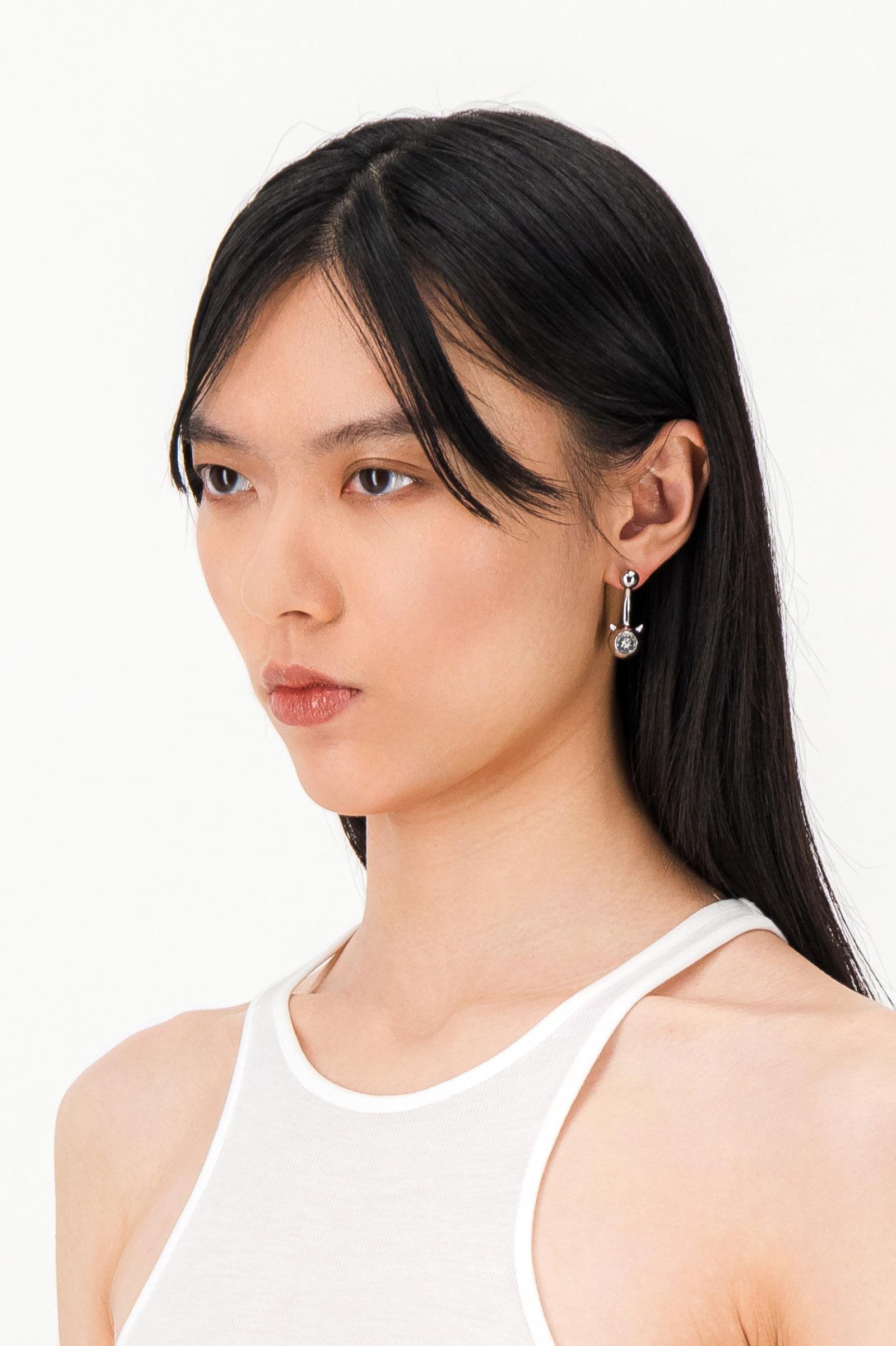 Side view of a model wearing the Justine Clenquet Evil Earrings Crystal